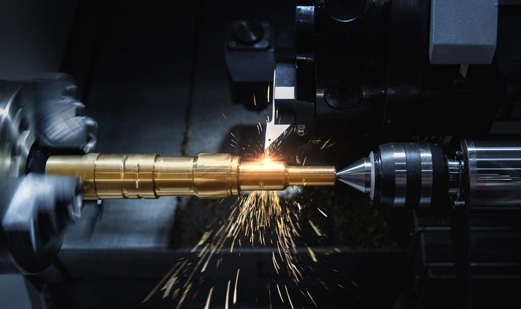 A CNC lathe removes material from a long, round piece of metal