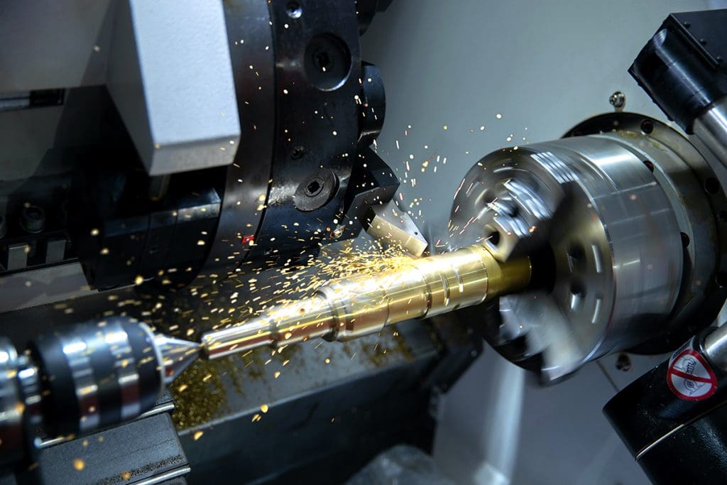 a metal lathe in action, with sparks and flakes of metal flying off of a spinning metal rod.