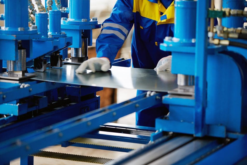 A metalworker using a press to shape a sheet of steel